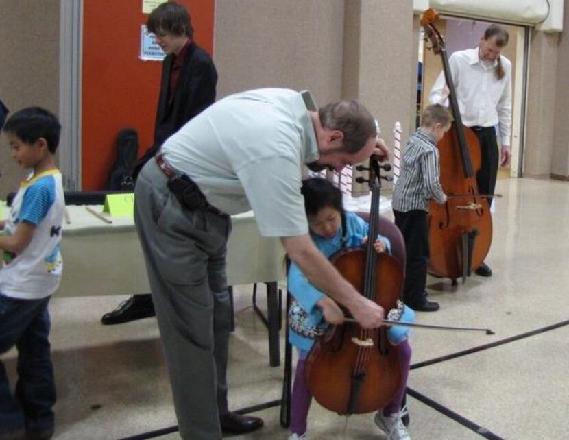 
Neil Ferguson helps a young cellist during a past symphony event.

