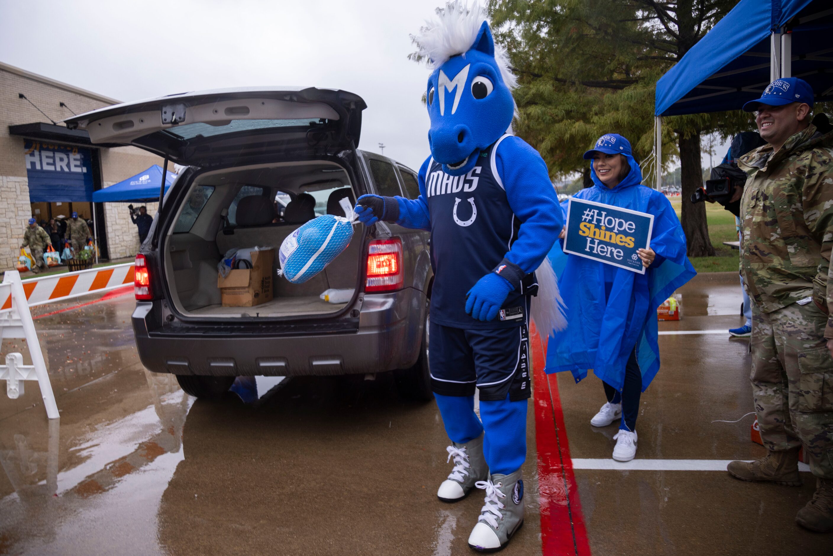 Champ, the Dallas Mavericks mascot, holds a turkey while loading cars during the Hoops for...