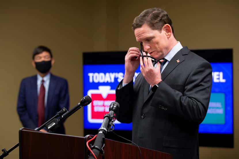 Dallas County Judge Clay Jenkins puts on his mask during a press conference where he spoke...