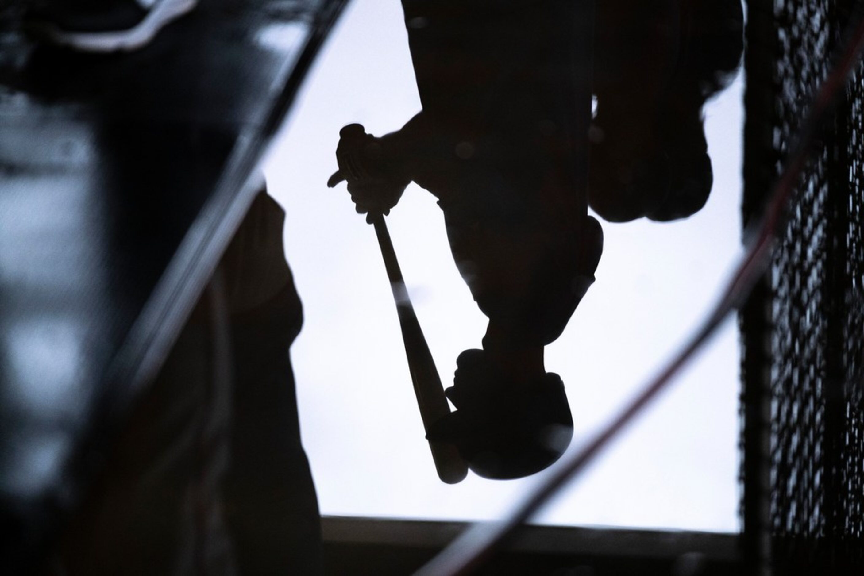 A player if reflected in a puddle inside the batting cages as weather moved all  baseball...