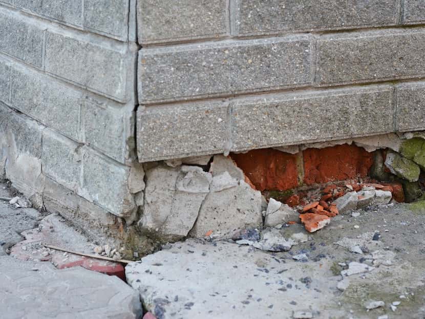 gray brick structure with cracking along the bottom
