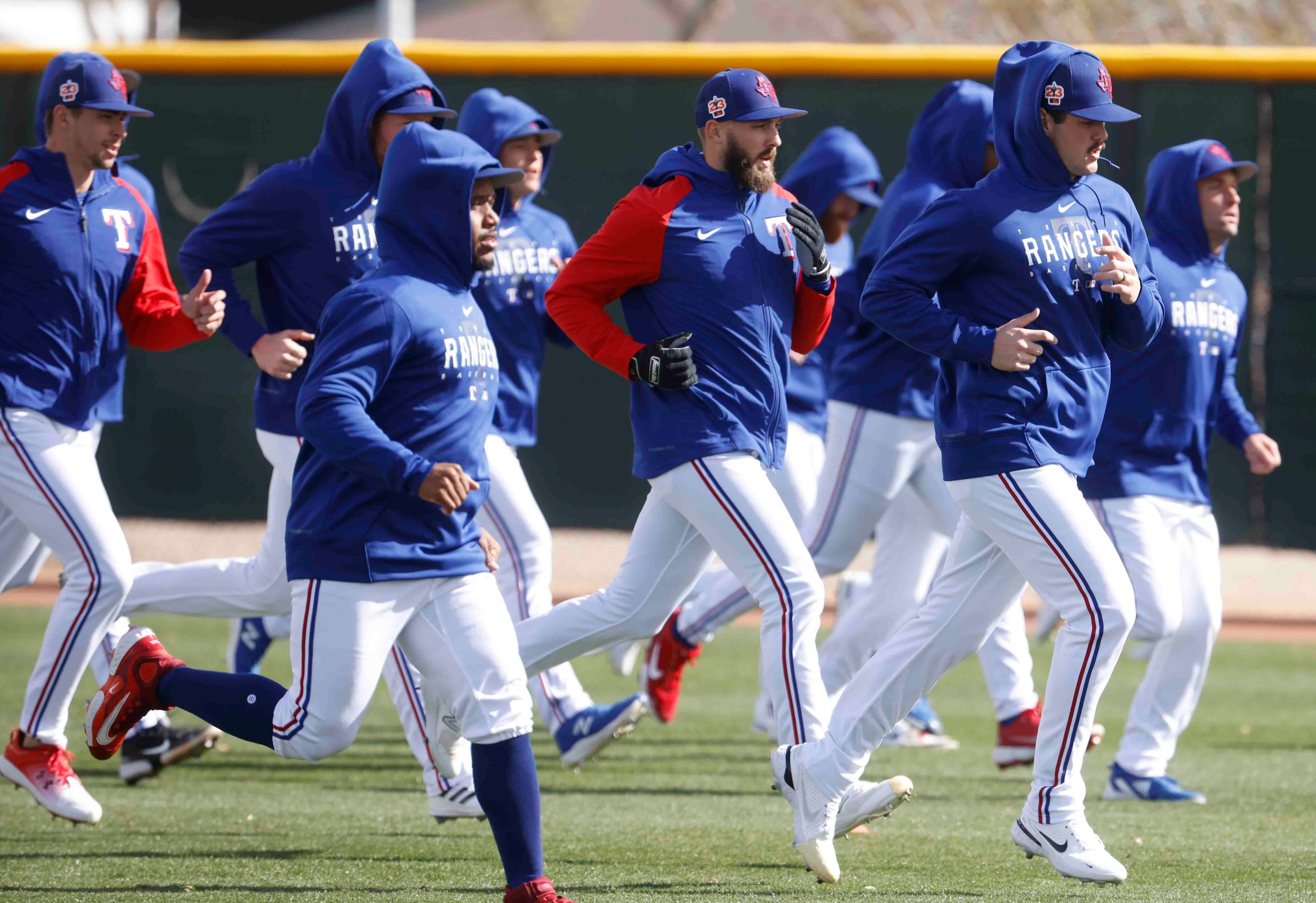 Texas Rangers pitchers Joe Barlow, center, Cole Ragans, right, jog with their teammates...