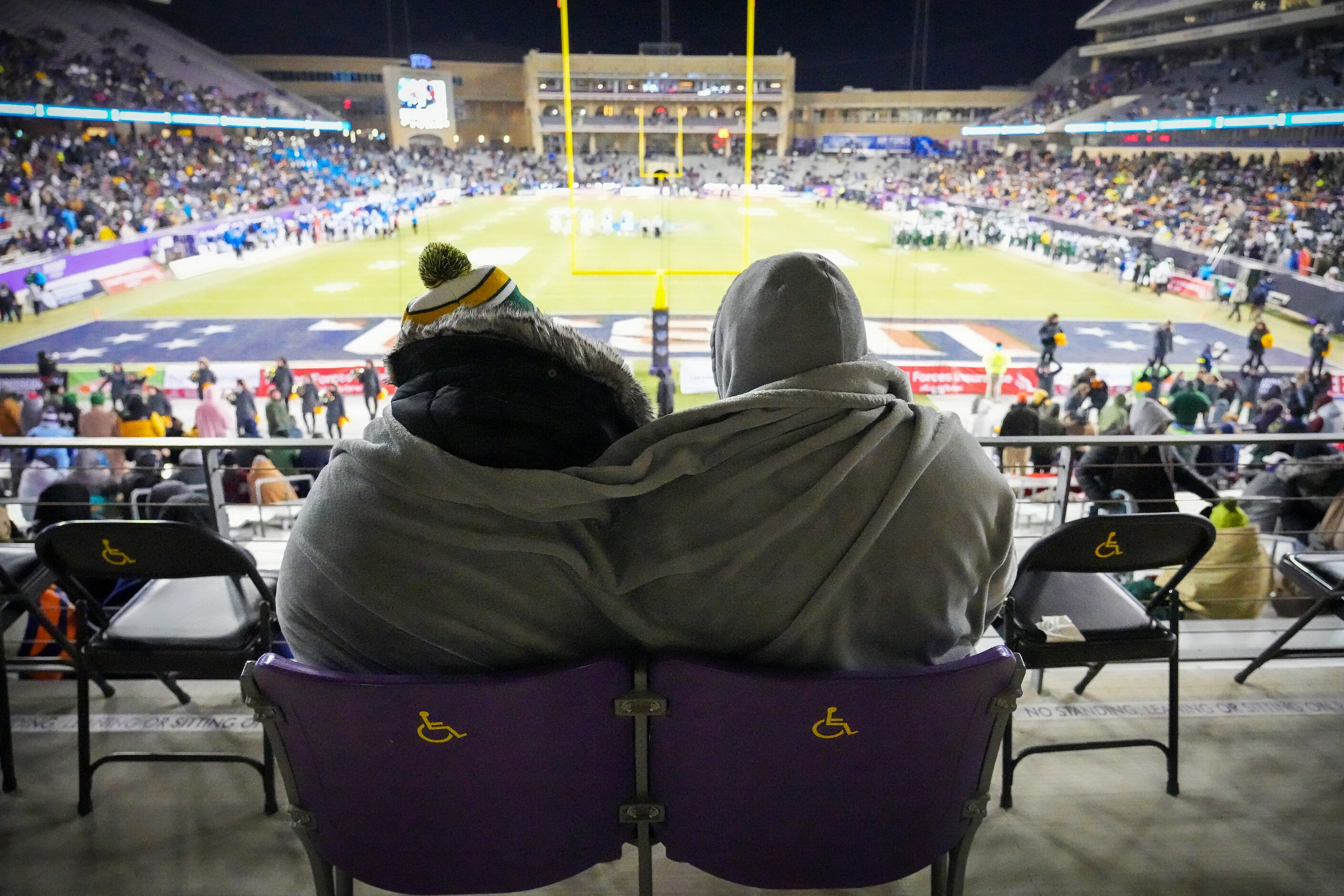 Fans huddle against cold temperatures during the first half of the Armed Forces Bowl NCAA...