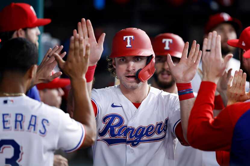 Texas Rangers DJ Peters is congratulated by teammates after scoring on Brock Holt's go-ahead...