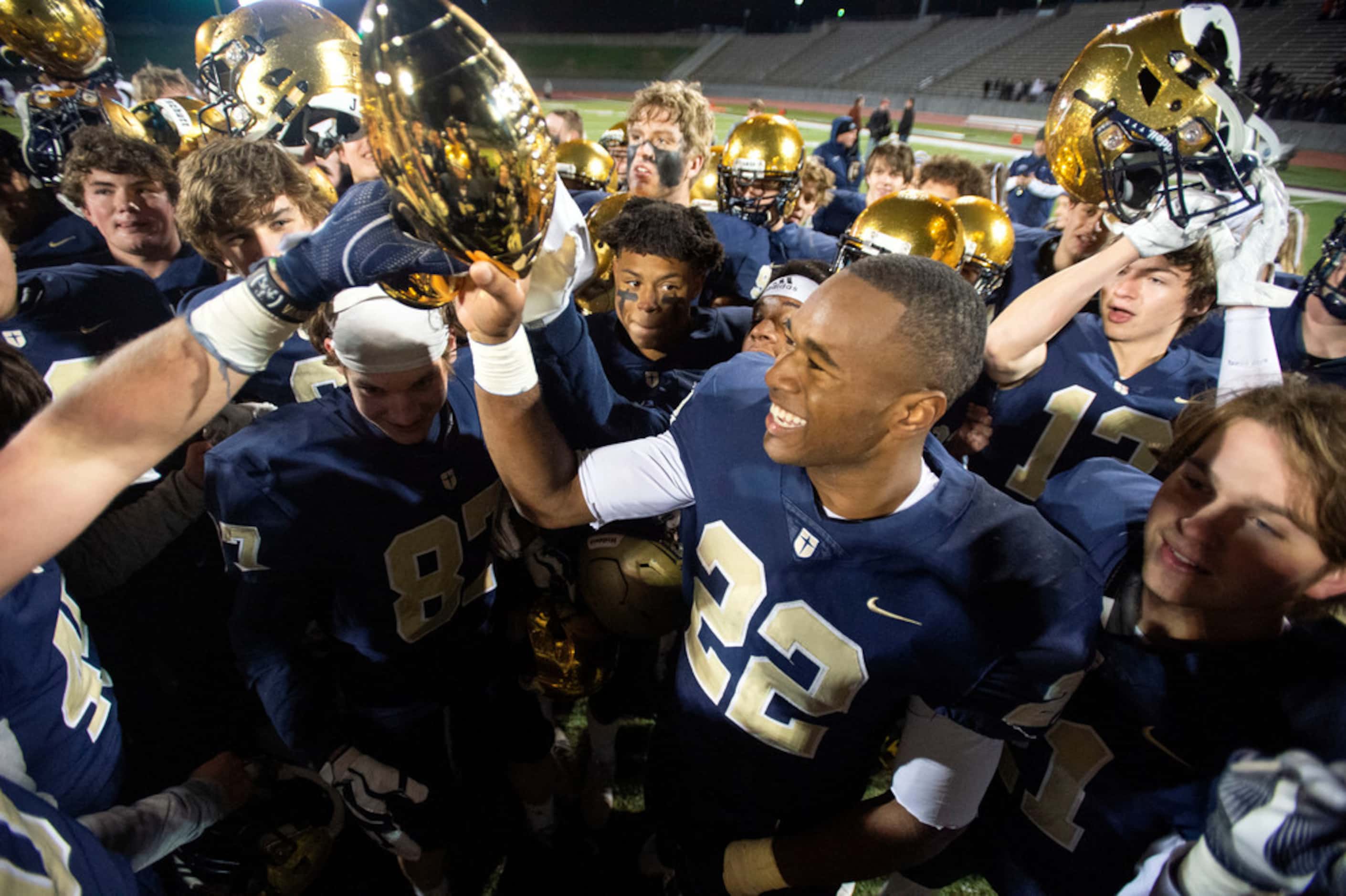 Jesuit senior running back E.J. Smith (22) raises the trophy after his team's 27-25 victory...