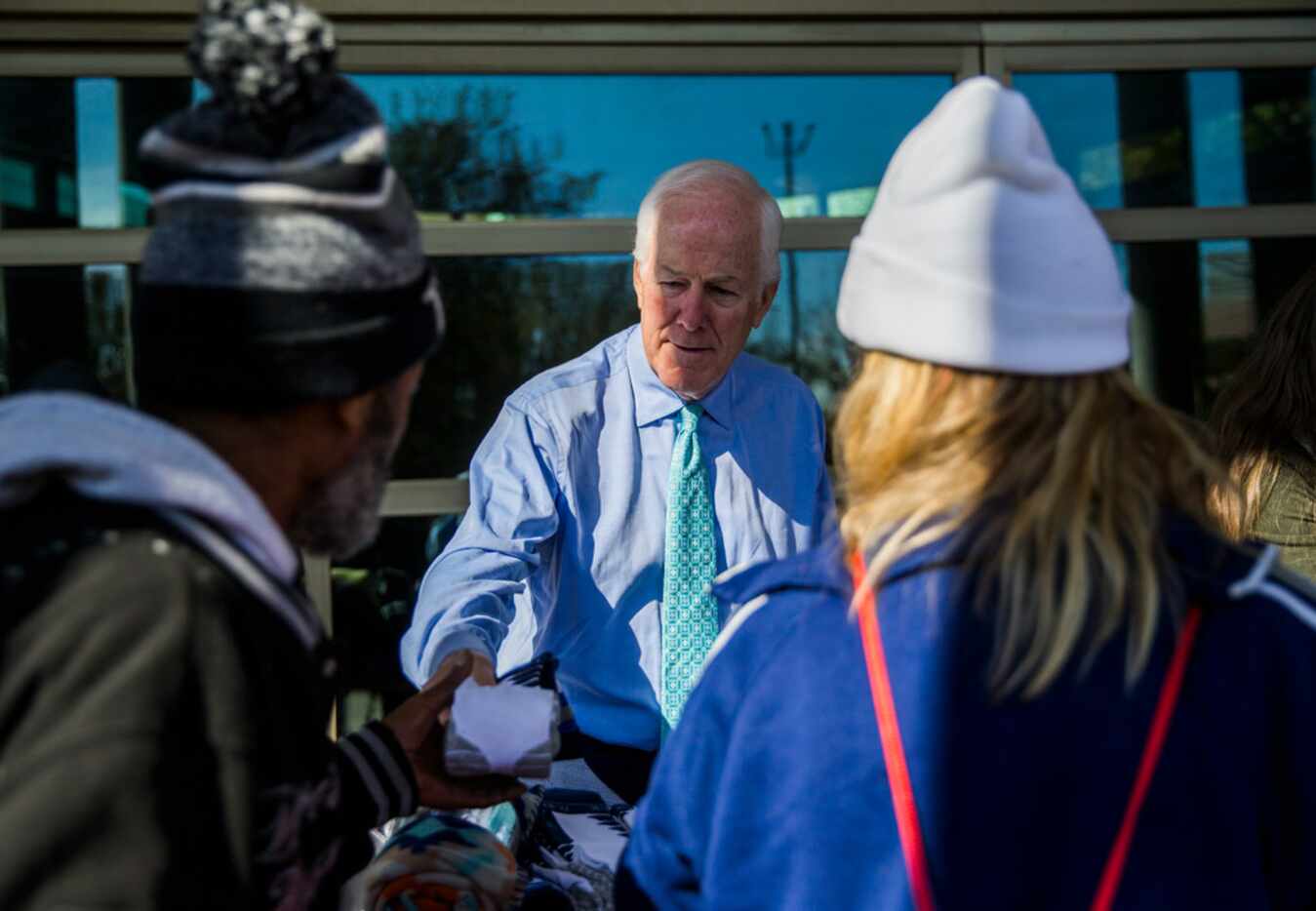 U.S. Senator John Cornyn hands out socks, sweatshirts and other clothing to homeless people...