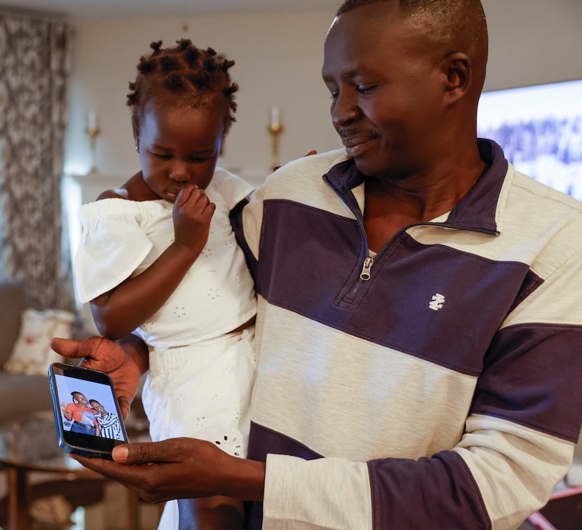 Jacob Mabil, carrying his daughter Agot, 2, who came to the U.S. through the U.S. refugee...