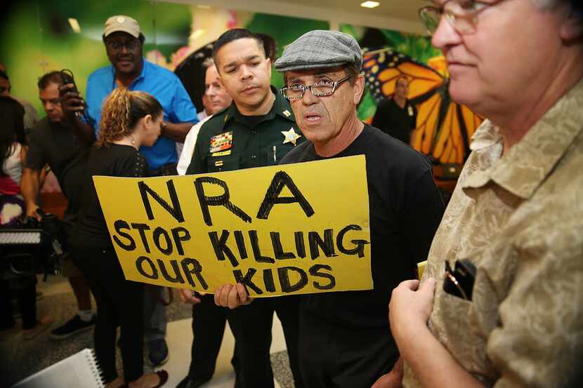 A protester holds a sign that reads, "NRA Stop Killing Our Kids," outside the courtroom...