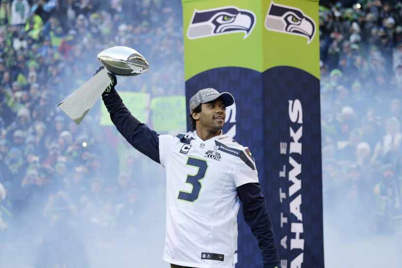 Seattle Seahawks quarterback Russell Wilson  carries the Vince Lombardi Trophy as he walks...