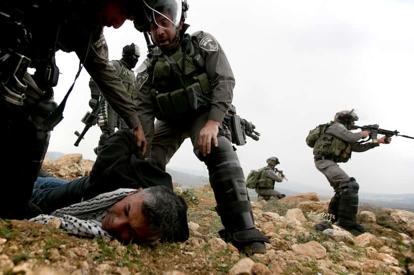 Israeli border police officers detain a Palestinian protester following a prayer for...