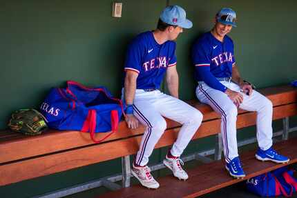 Texas Rangers outfielders Wyatt Langford (right) and Evan Carter laugh in the dugout before...