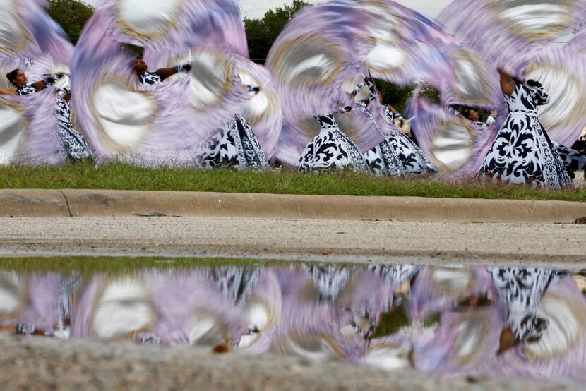 Red Oak Mighty Hawk Band color guard members, practicing in the parking lot, were reflected...