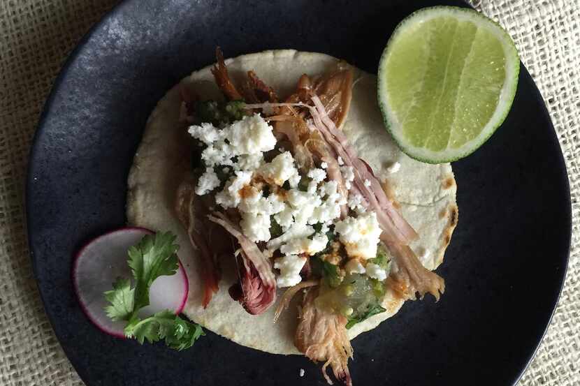 A taco  with smoked chicken, salsa verde and queso fresco on a homemade corn tortilla