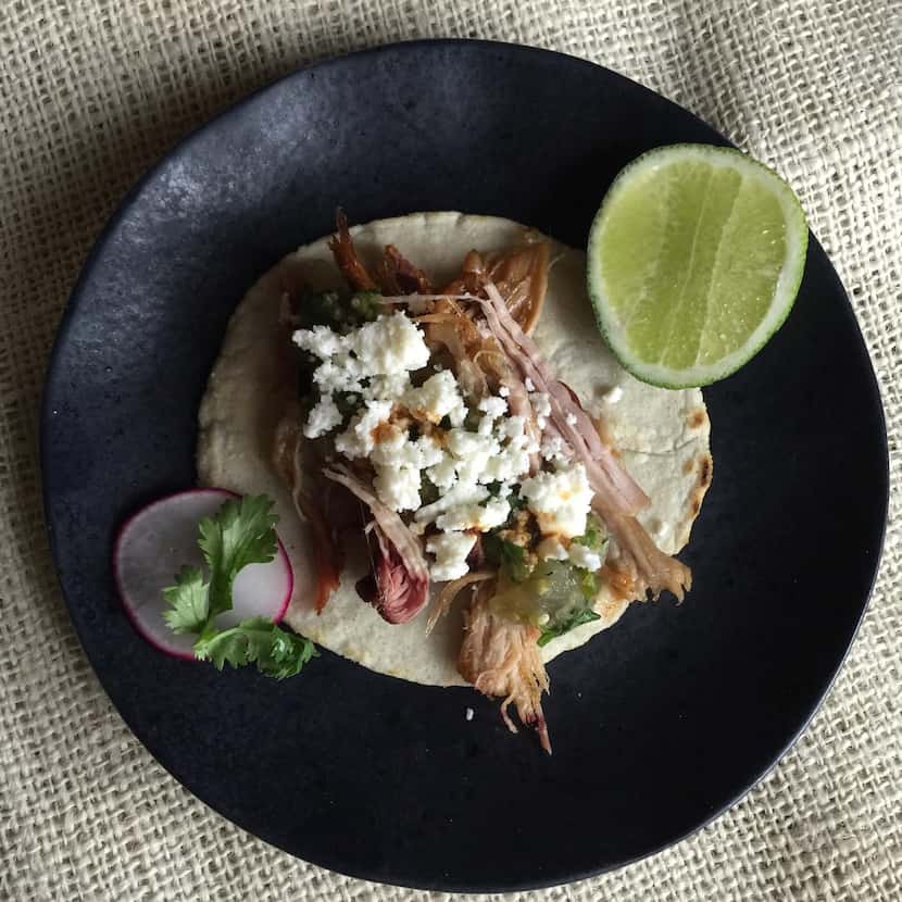 A taco  with smoked chicken, salsa verde and queso fresco on a homemade corn tortilla
