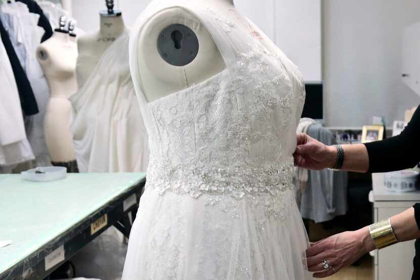 A David's Bridal employee arranges a dress on a plus-size mannequin in New York. 
