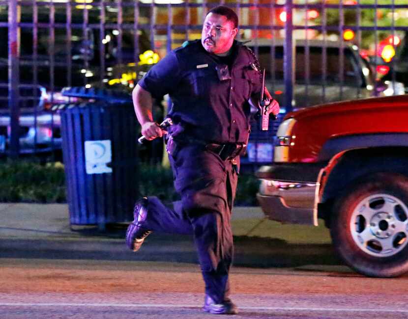 A Dallas Police Department officer runs for cover during the chaos that followed a deadly...