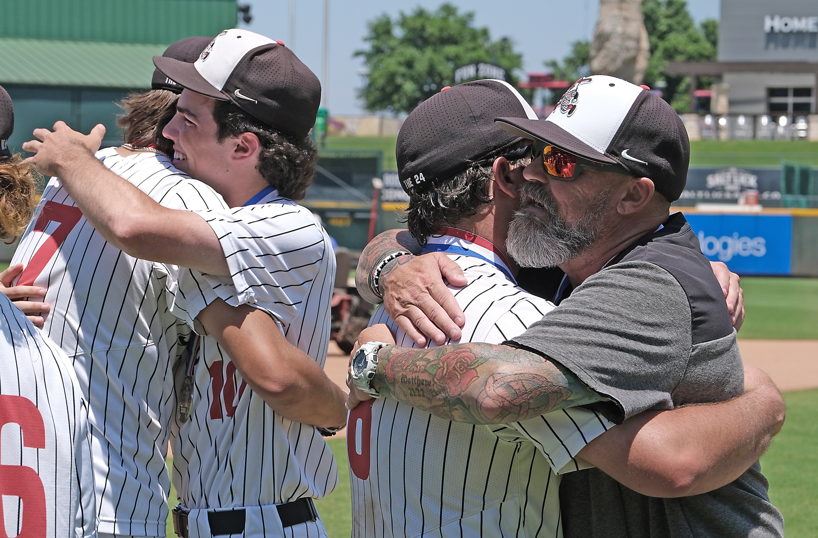 Argyle head coach, Ricky Griffin, gives Hunter Sandifer, (8), a hug as Park Prater, (7), and...