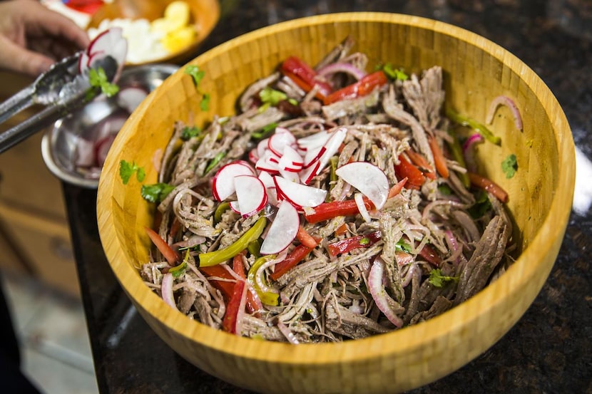 Monica Greene adds ingredients to the salad while preparing ropa vieja.