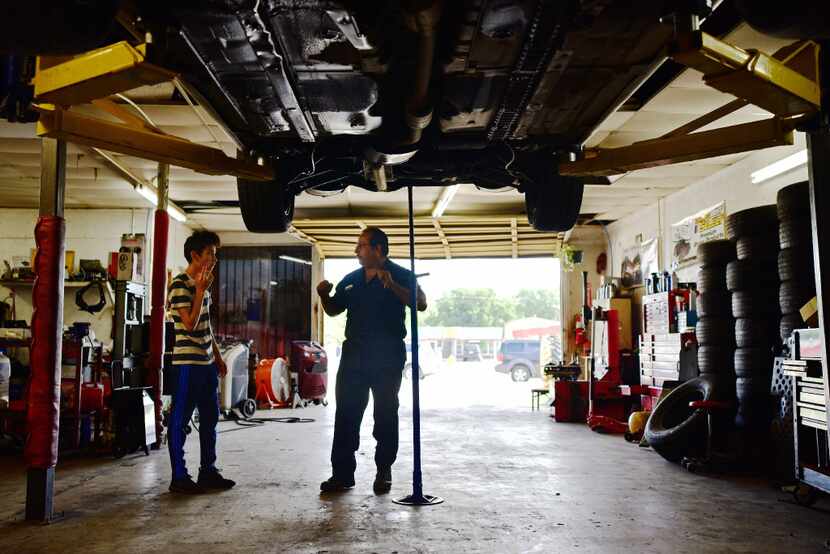 Joaquin Godinez chats with his son Cristian Godinez at his auto mechanic shop.
