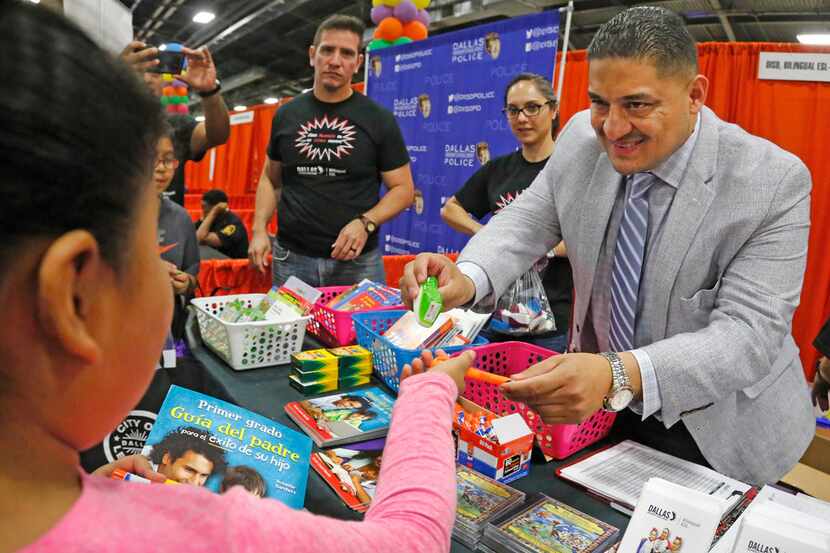 Dallas school board member Jaime Resendez hands out items to parents and students at the...