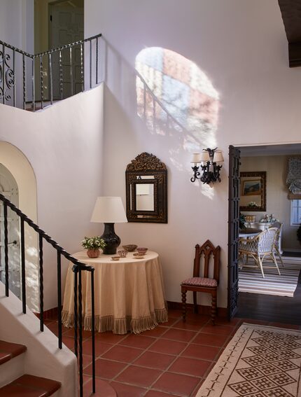 Entry hallway with a round table covered with a tablecloth, lamp and trays