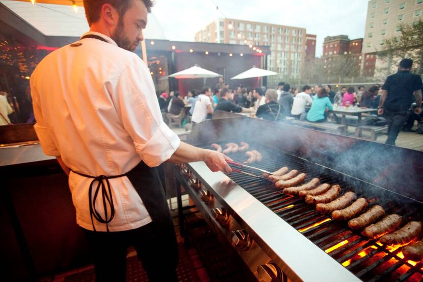 A cook grilling sausages on FoodLab's terrace.