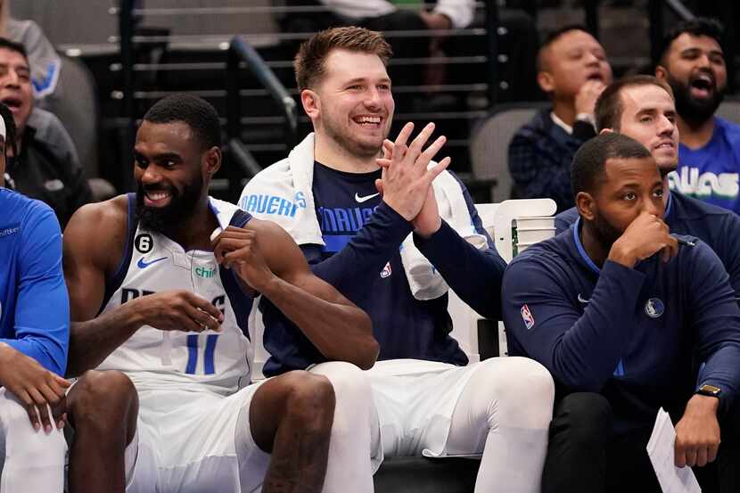 Dallas Mavericks guard Luka Doncic, center, watches from the bench with teammate forward Tim...