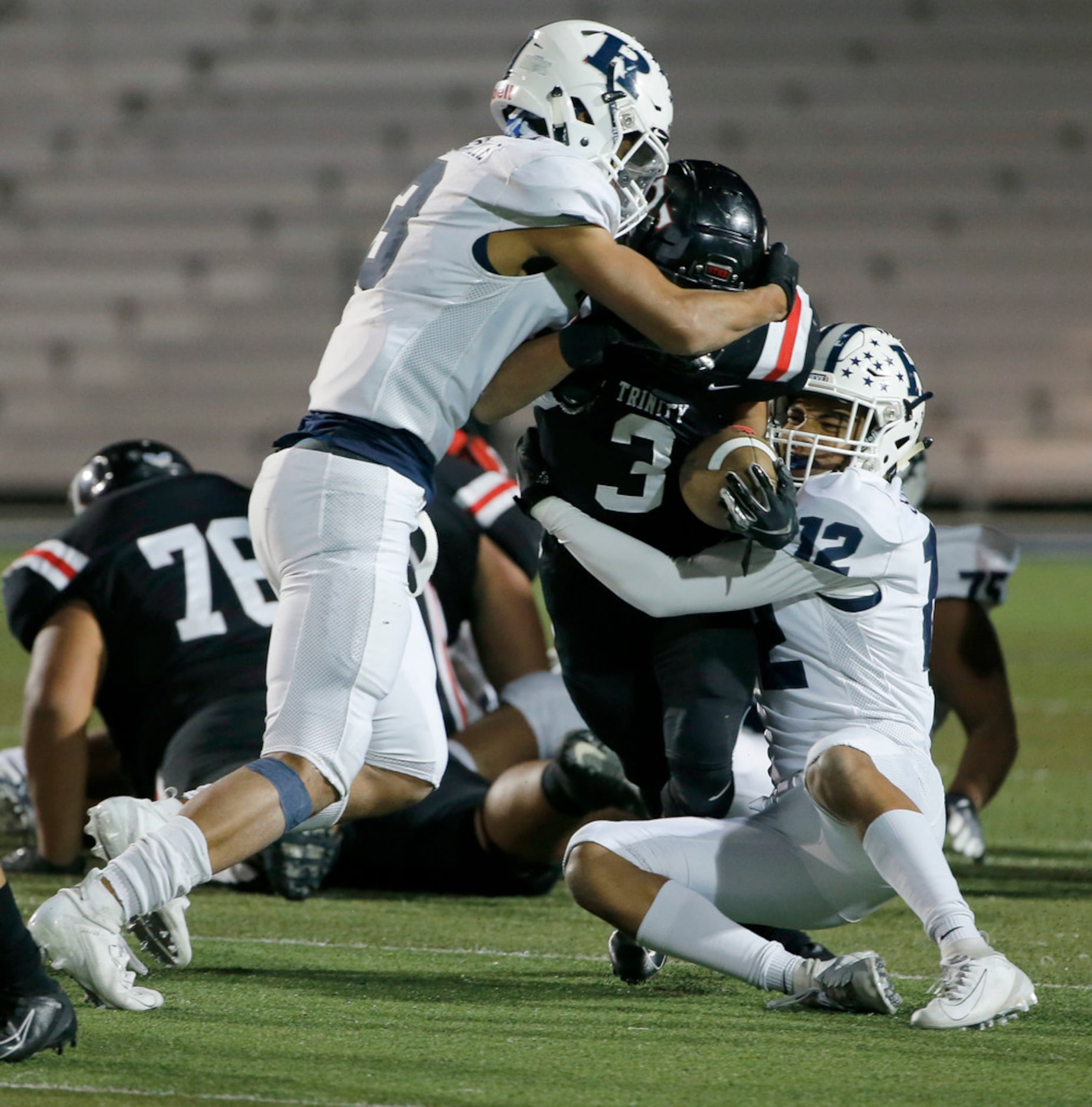 Richland's C.J. Baskerville (3) and Paul Samuel (#12) tackle Trinty running back Zechariah...