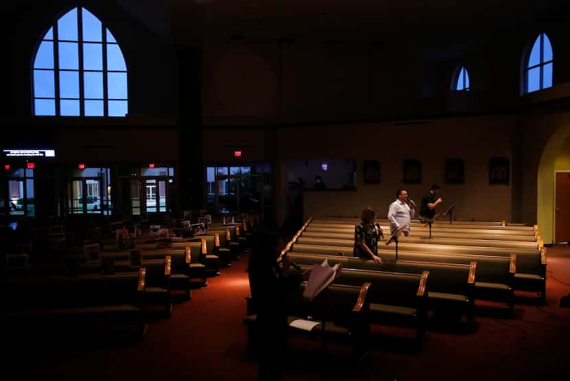 Adequately spaced in pews, a handful of singers perform as the alter is stripped following...