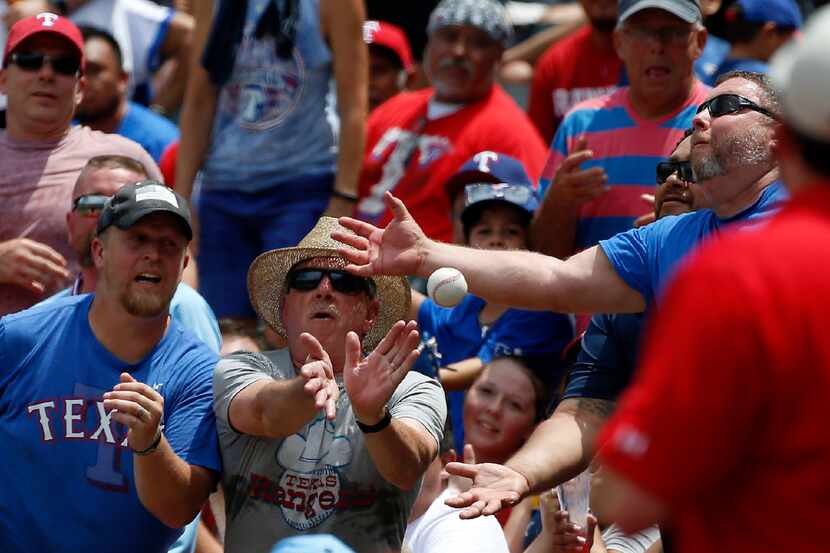 Fans reach for the foul ball in the stands during the Texas Rangers and Los Angeles Angels...