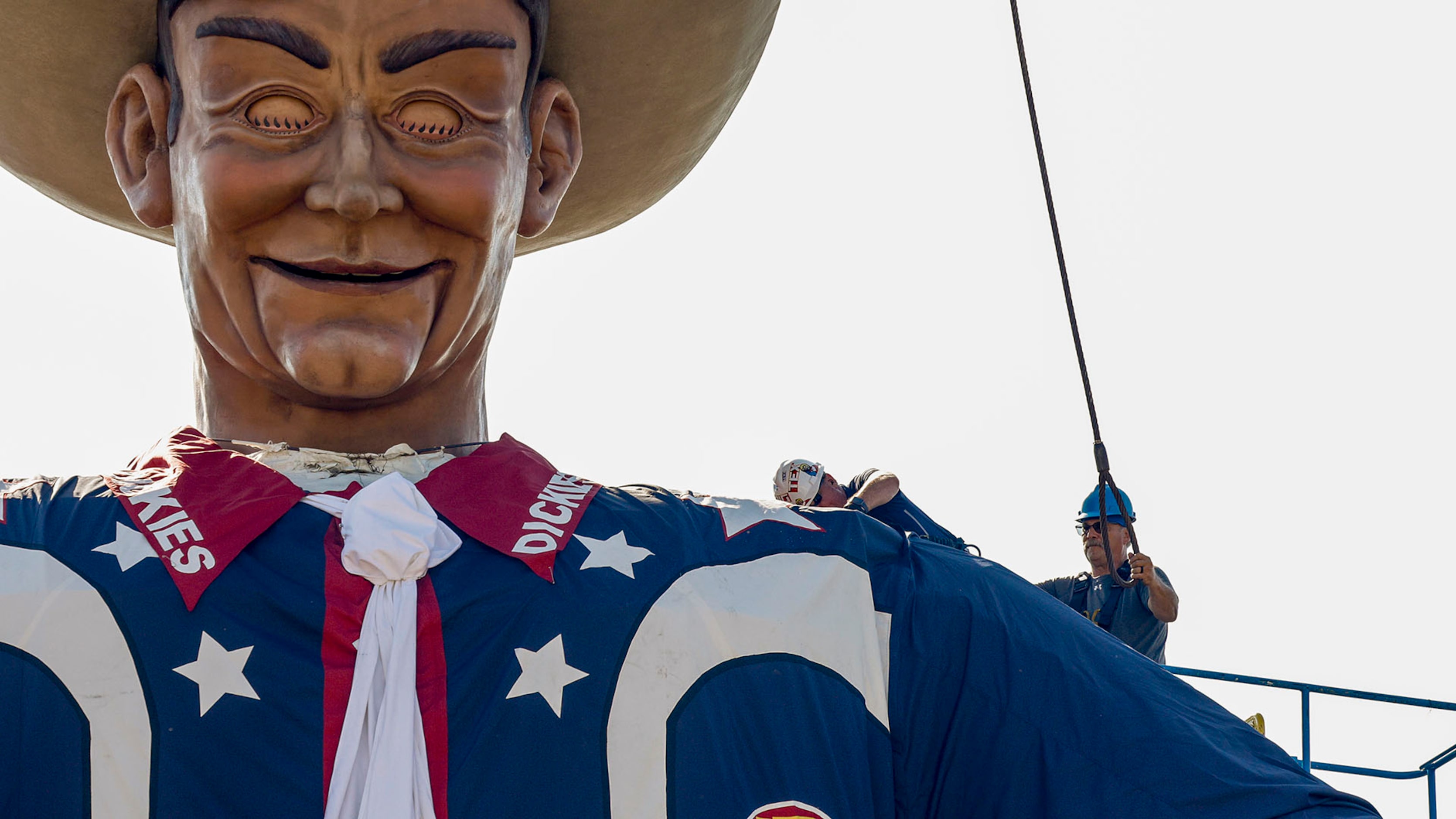 Crews remove one of the steel cables used to lift Big Tex at The State Fair of Texas,...