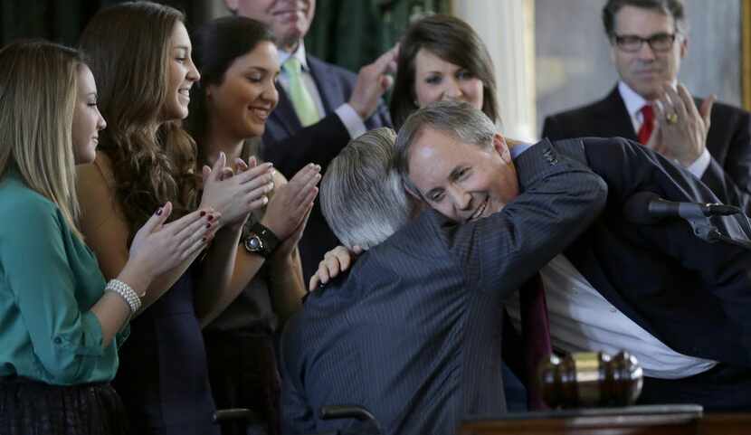 Ken Paxton (right) embraced Gov.-elect Greg Abbott after Paxton was sworn in as Texas...