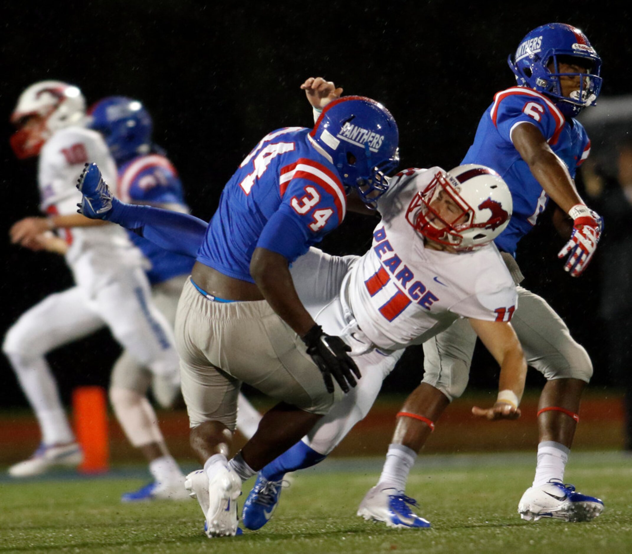 Richardson Pearce quarterback Bo Brewer (11) takes a crushing hit from Duncanville defenders...