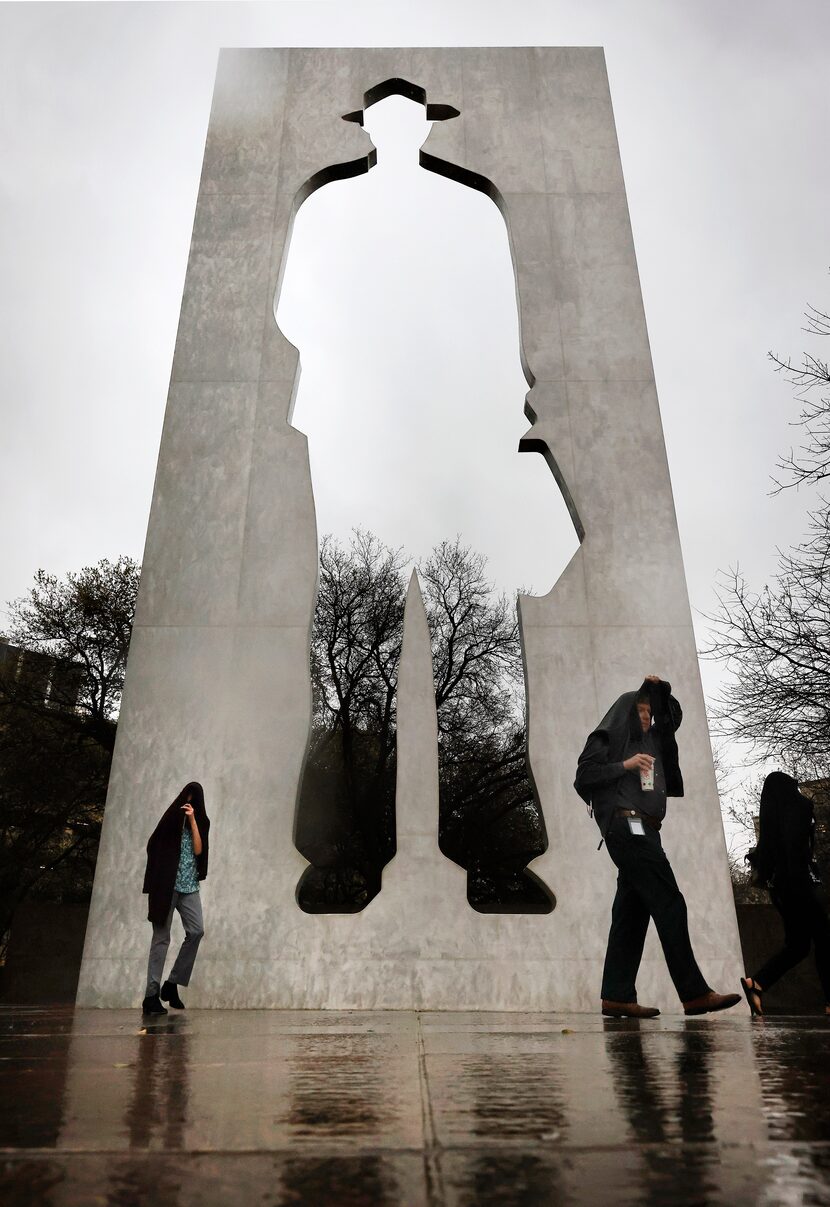 People on their lunch hour scurried through the rain and past the towering Man With A...