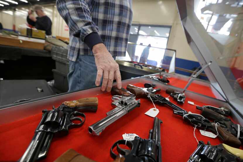 A dealer arranges handguns in a display case in advance of a show at the Arkansas State...