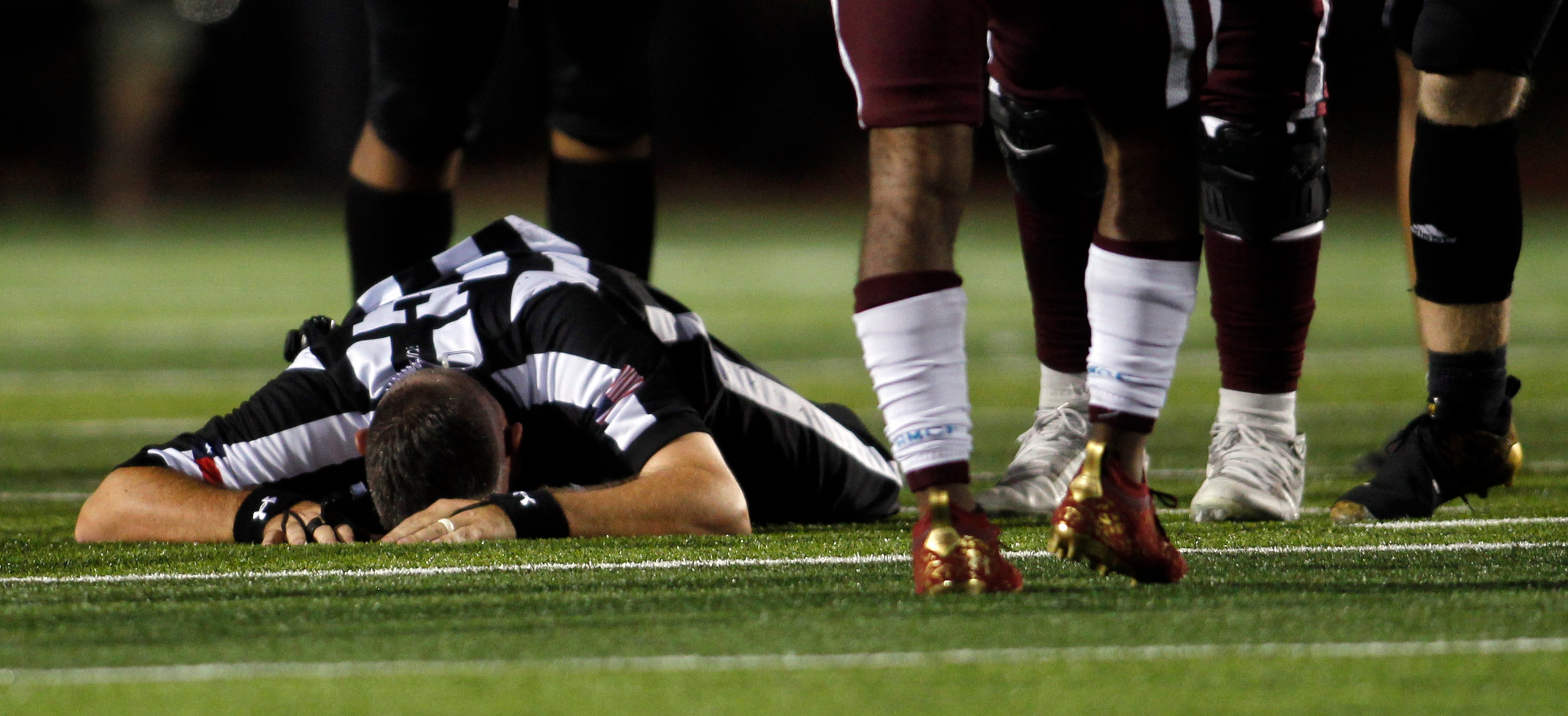 Umpire Eric Horton lies on the turf after colliding with a Hebron receiver in the Plano...