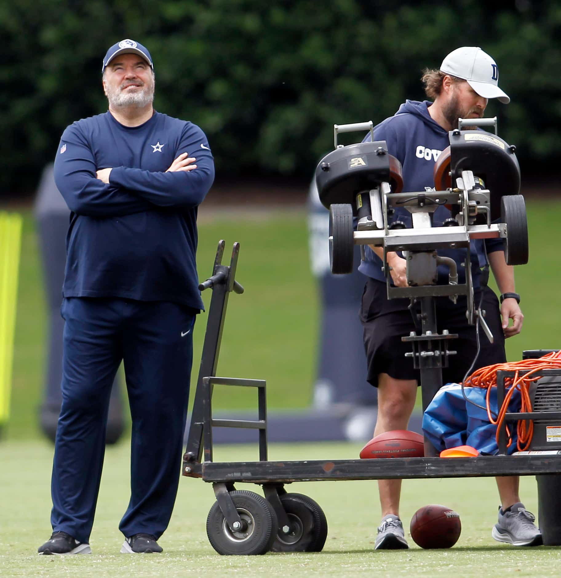 Dallas Cowboys head coach Mike McCarthy, left, watches as a football is sent skyward as a...