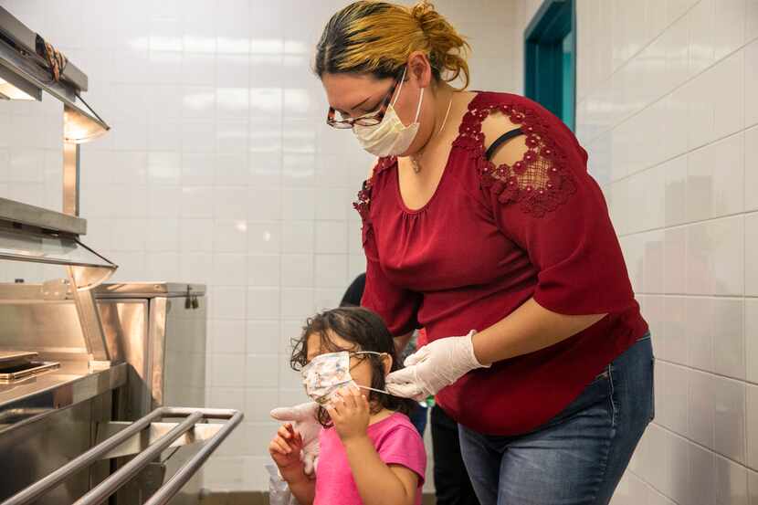 Angie Andrade readjusted her 3-year-old daughter Abigail’s face mask while they picked up...
