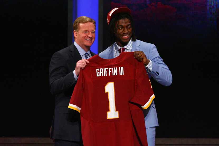 Robert Griffin III (R) from Baylor holds up a jersey as he stands on stage with NFL...