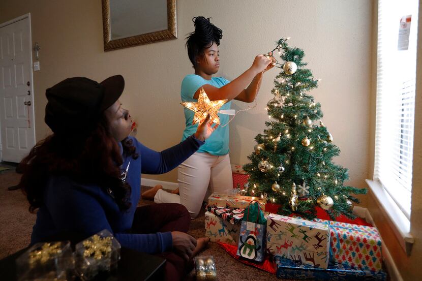 Ebony Green, left, and her daughter Amaris Dobbins decorates their Christmas tree in their...