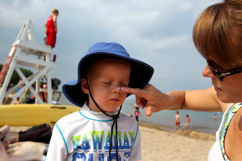 Kristin Conn applies a non-nano sunscreen to her son, Merrick, at Lee Street Beach in...
