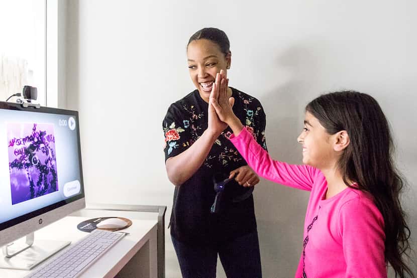 Courtney Johnson, process manager at Capital One, high-fives Carmen Sanchez, 9, of Dallas...