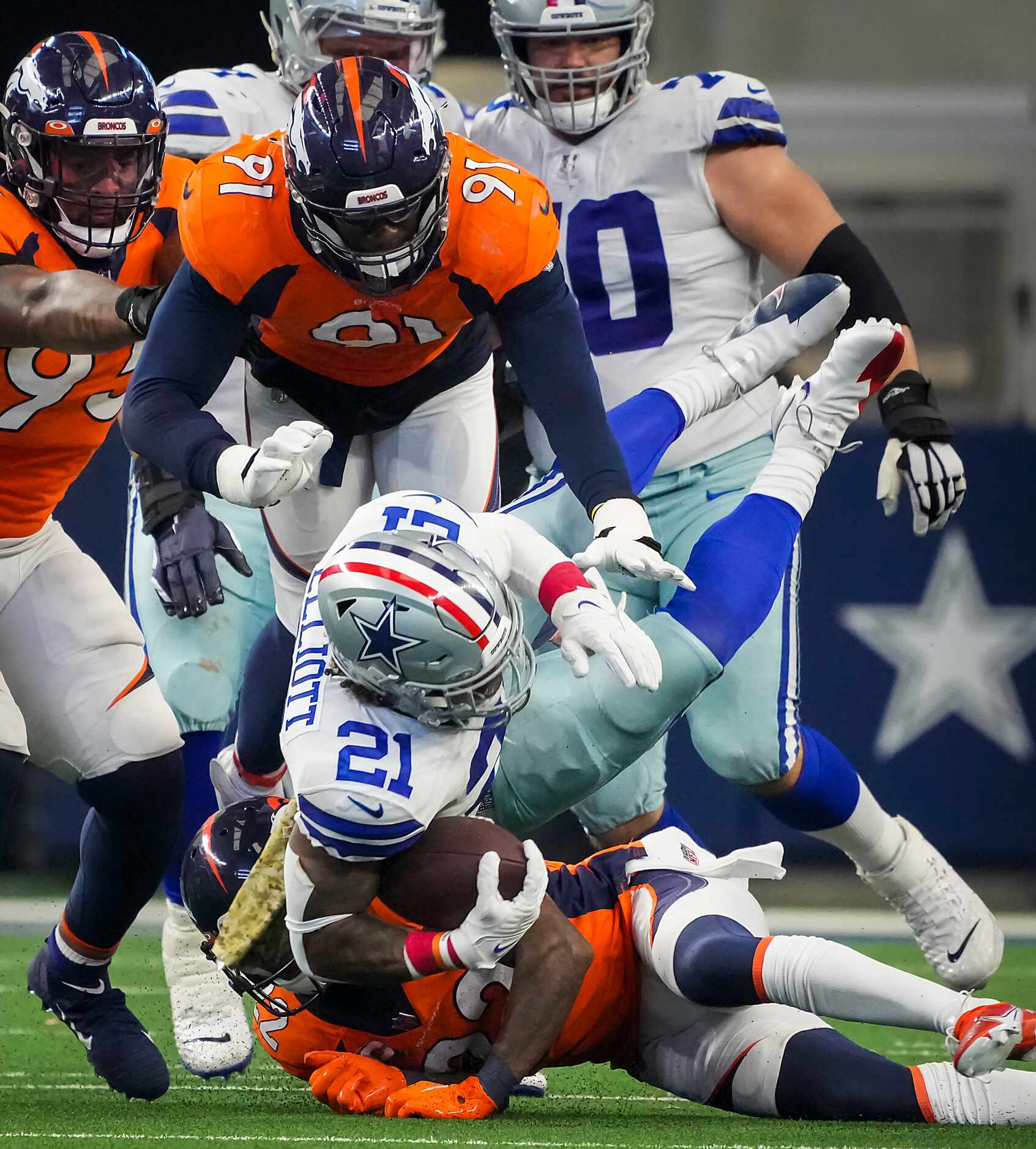Dallas Cowboys running back Ezekiel Elliott (21) is knocked off his feet by Denver Broncos...