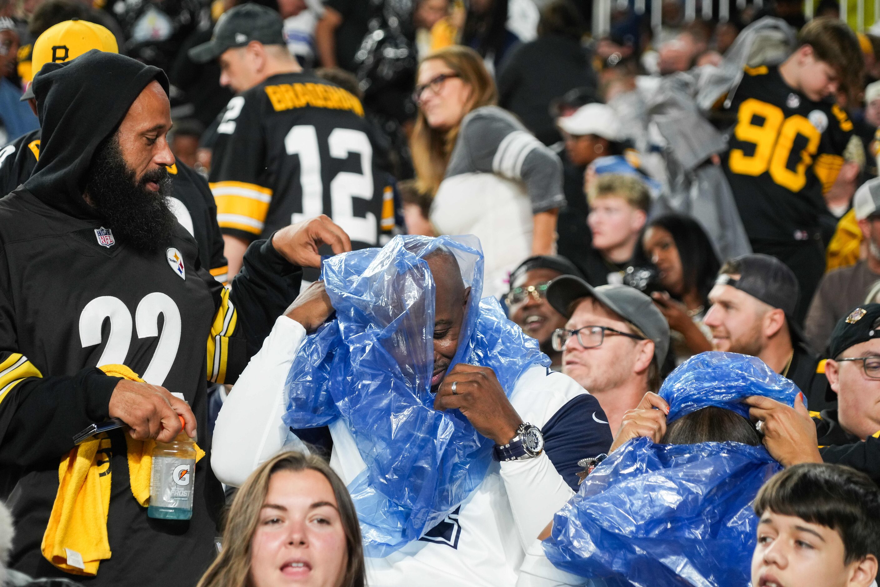 Fans don rain ponchos during a weather delay before an NFL football game between the...