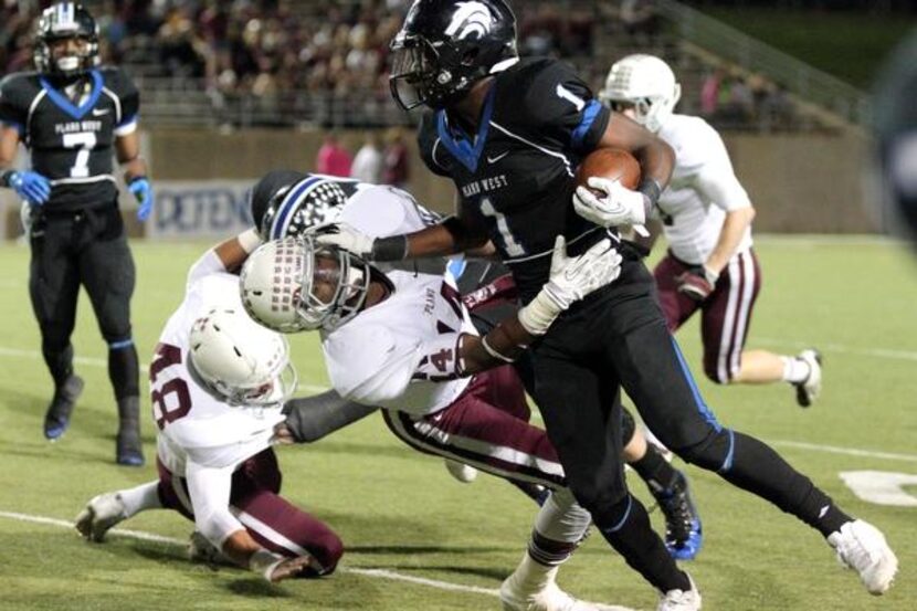 Plano West running back Sotonye Jamabo (1) tries to repel Plano linebacker David Griffith...