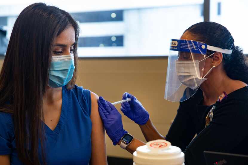 COVID unit nurse Perla Sanchez-Perez (left) receives a dose of the Pfizer COVID-19...