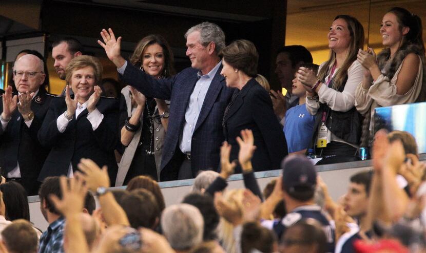 Former President George W. Bush acknowledges the cheers of the crowd during a time out in...
