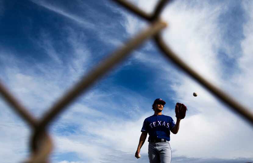 Texas Rangers starting pitcher Yu Darvish (11) lifts his glove to catch a pass as he throws...