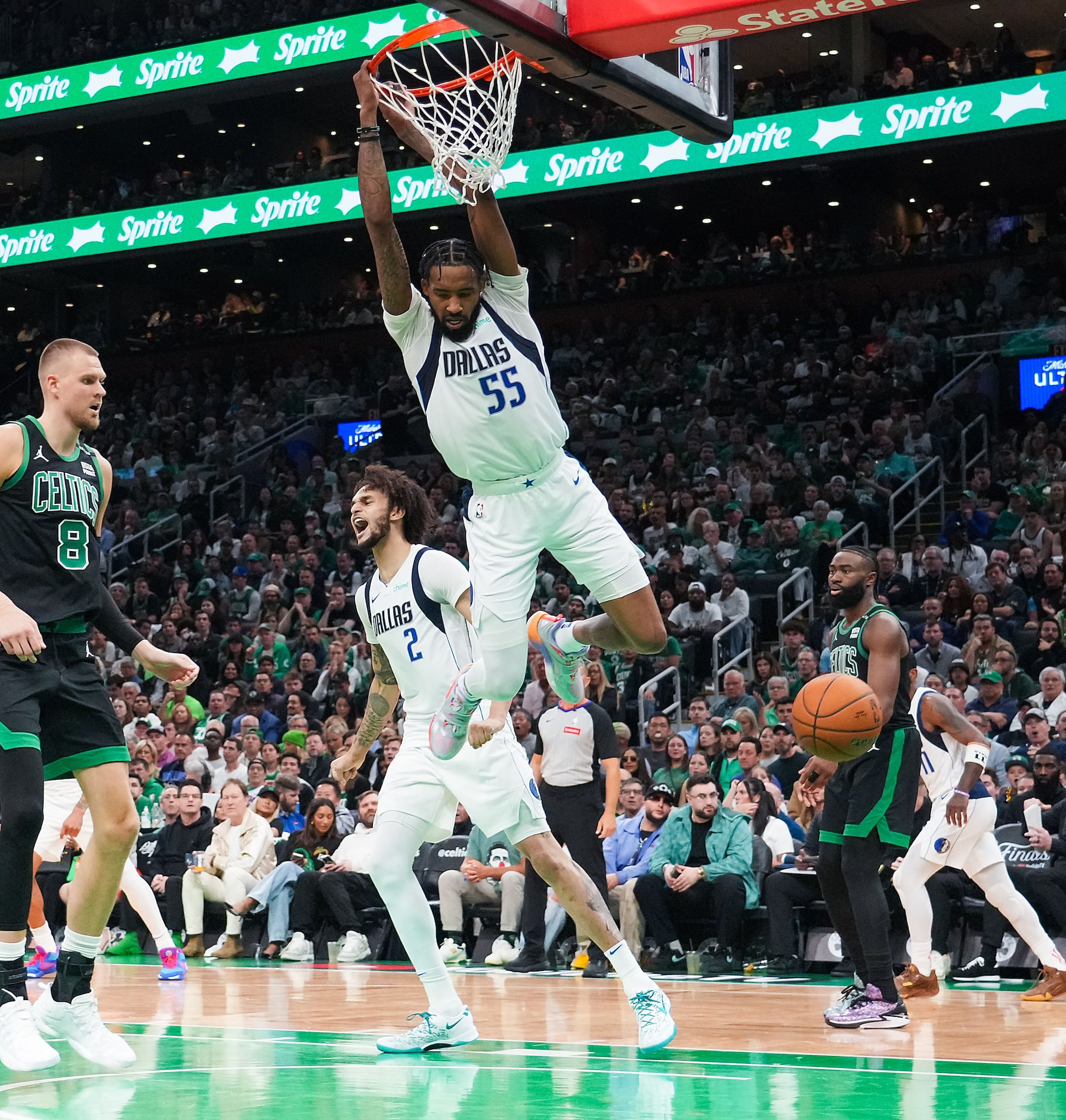 Dallas Mavericks forward Derrick Jones Jr. (55) hangs on the rim after a dunk past Boston...