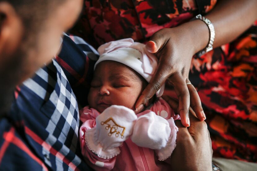 Derrick (left) and Mech Metiege hold Sekani, their daughter who was born during Sunday...